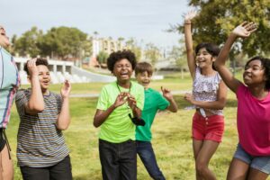 Group of diverse children playing and laughing outside in a sunny park.